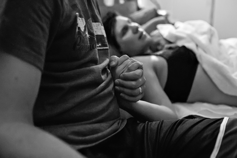 Image of a husband holding his wife's hand through postpartum contractions.