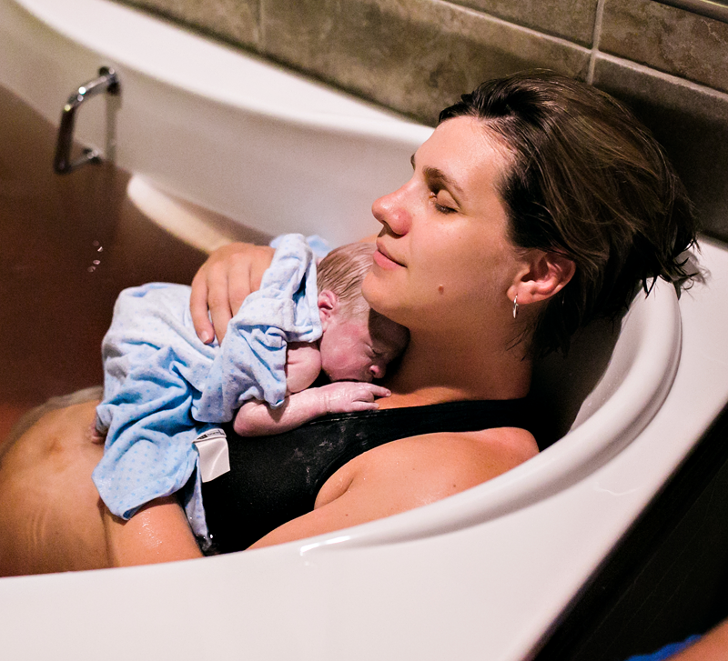 Image of a mother in a birthing pool, holding her newborn baby.