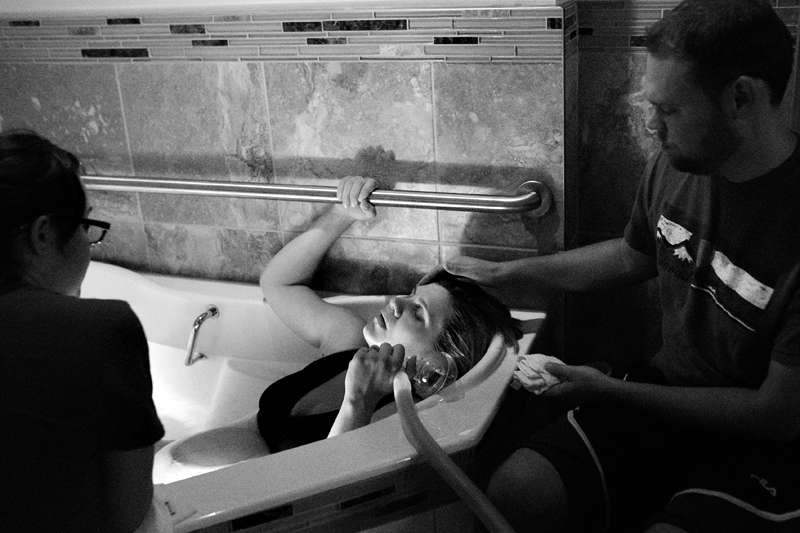 Image of a laboring mother in a birthing tub, holding nitrous oxide.