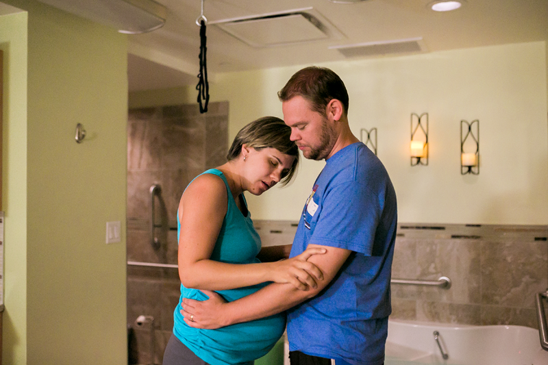 Image of a laboring woman leaning on her partner for support.