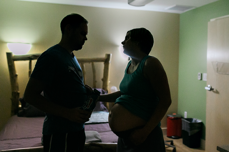 Silhouette of a laboring woman leaning on her partner for support.