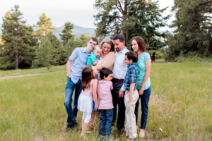 Family of eight snuggle with Colorado mountain view.