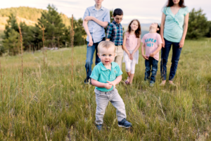 Toddler walking away from siblings with Colorado mountain view.